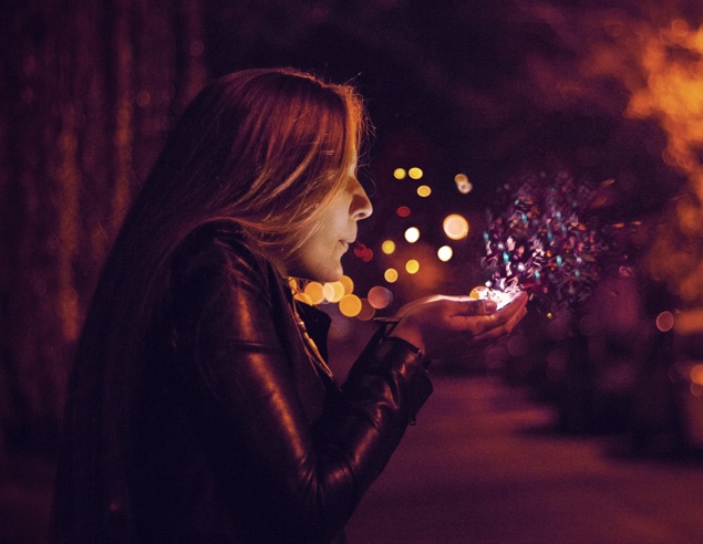 Woman blowing a handful of confetti into the air