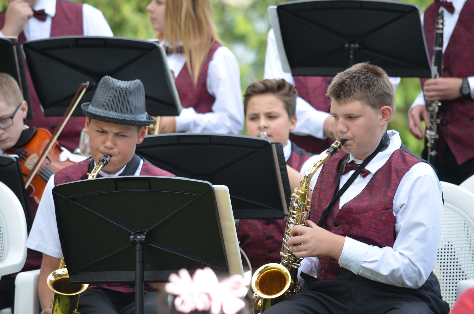 Photo of a school band in matching red vests. One boy wears a fedora.