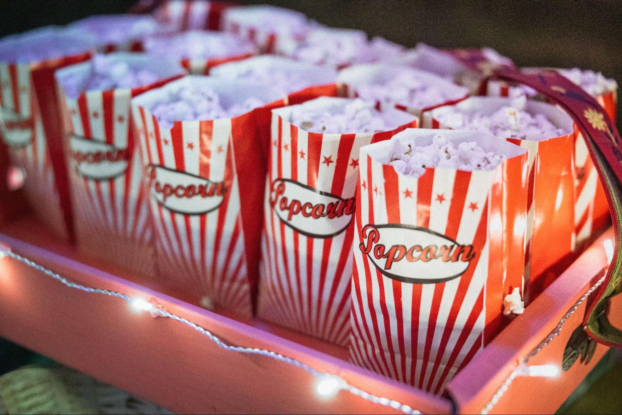 Bags of popcorn set out in a cute box with twinkle lights