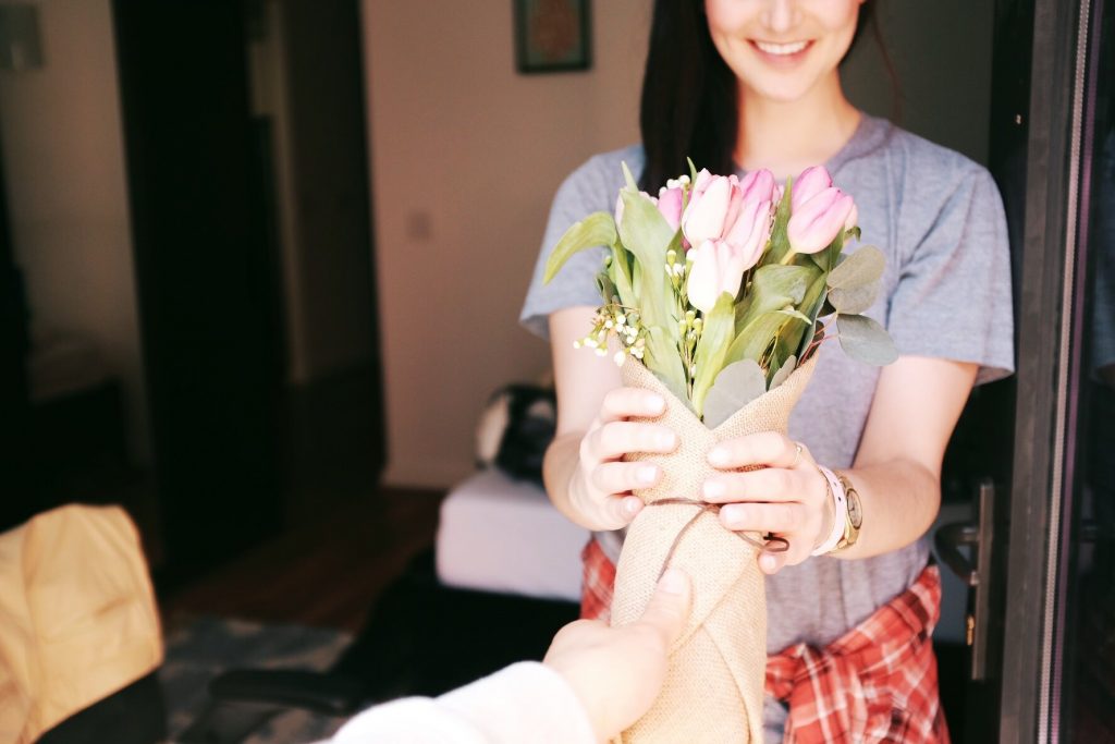 Someone hands a woman a bouquet of flowers as she smiles